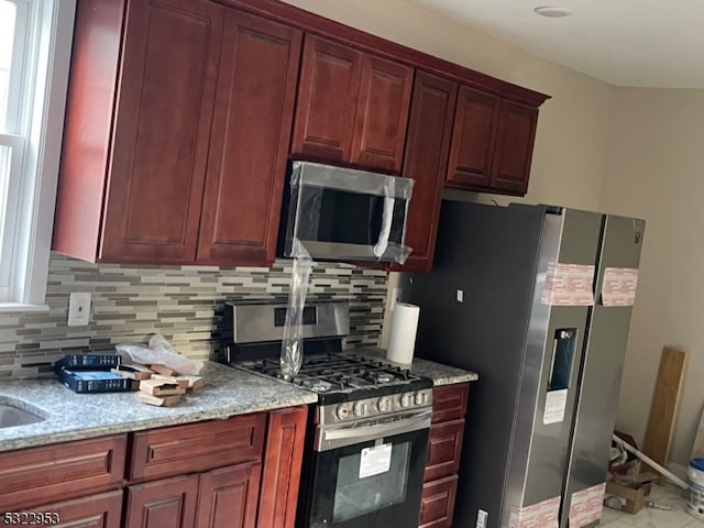 kitchen with backsplash, light stone countertops, and stainless steel appliances