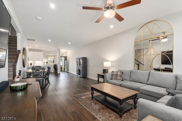 living room featuring dark wood-type flooring and ceiling fan