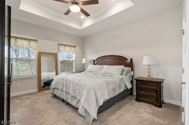 bedroom with light carpet, ceiling fan, and a raised ceiling