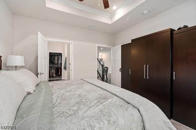 bedroom with a tray ceiling, ceiling fan, and carpet floors