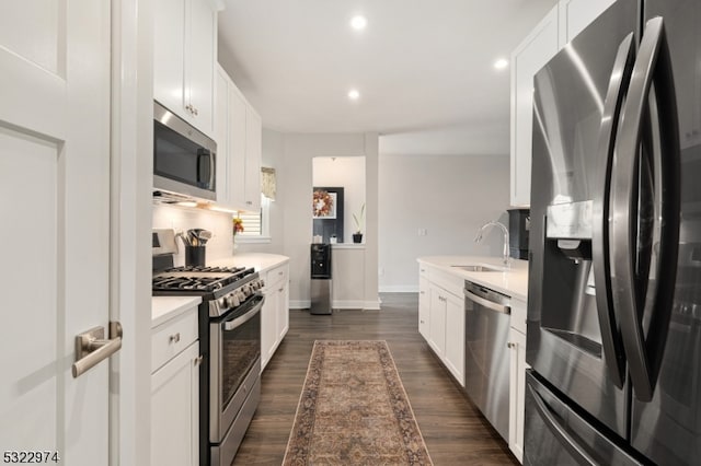 kitchen featuring stainless steel appliances, sink, dark hardwood / wood-style floors, white cabinets, and decorative backsplash