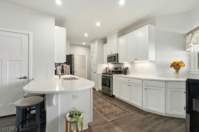 kitchen with stainless steel appliances, a kitchen breakfast bar, white cabinets, and sink