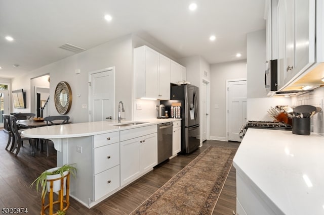 kitchen featuring white cabinetry, stainless steel appliances, a breakfast bar area, and dark hardwood / wood-style flooring