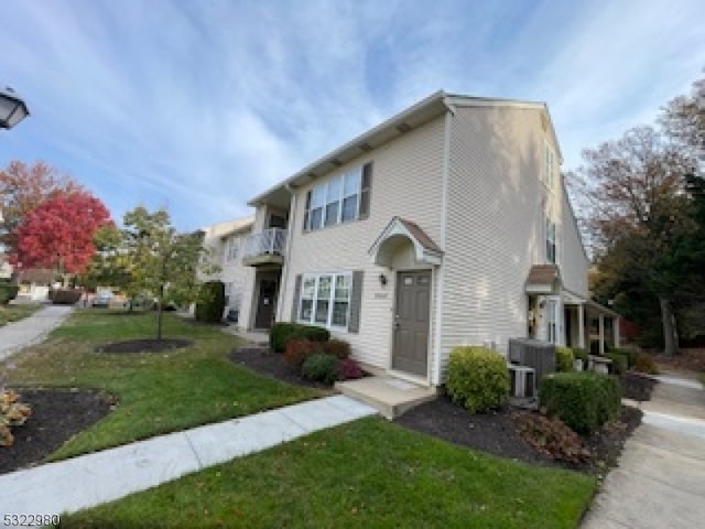 view of front of property featuring a front lawn, a balcony, and cooling unit