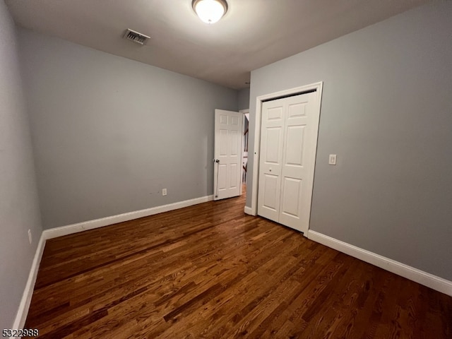 unfurnished bedroom featuring dark wood-type flooring and a closet