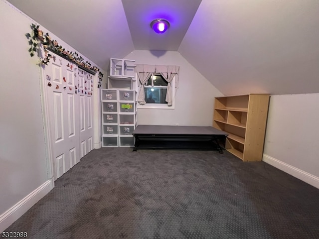 bonus room with dark colored carpet and lofted ceiling