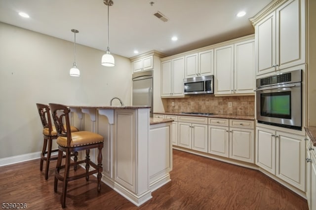 kitchen with dark hardwood / wood-style flooring, light stone counters, a center island, a breakfast bar area, and appliances with stainless steel finishes