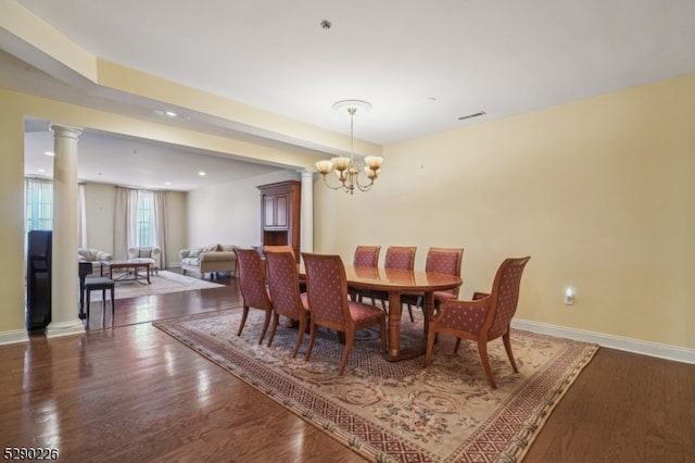 dining area featuring ornate columns, dark hardwood / wood-style flooring, and a chandelier