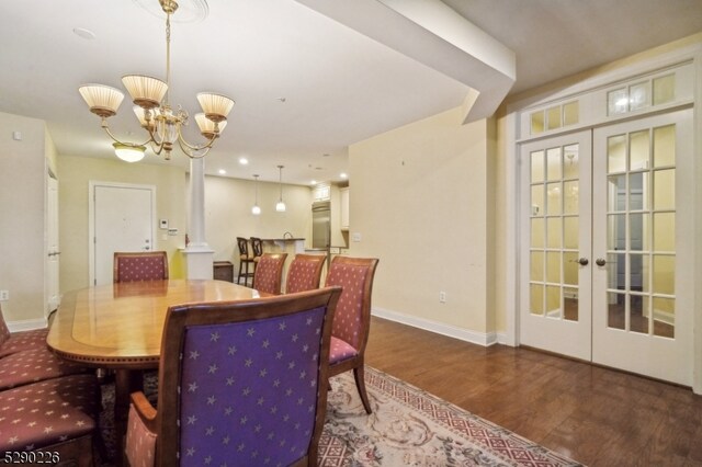 dining room featuring french doors, dark wood-type flooring, decorative columns, and a notable chandelier