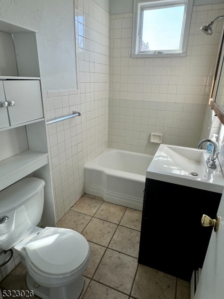 full bathroom featuring toilet, tile patterned floors, tile walls, tiled shower / bath, and vanity