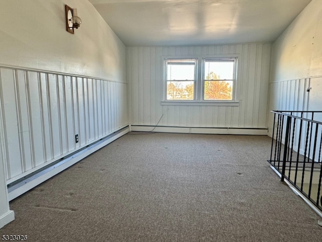 carpeted spare room with a baseboard heating unit