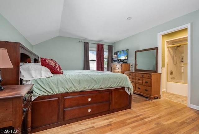 bedroom with vaulted ceiling, ensuite bathroom, and light wood finished floors