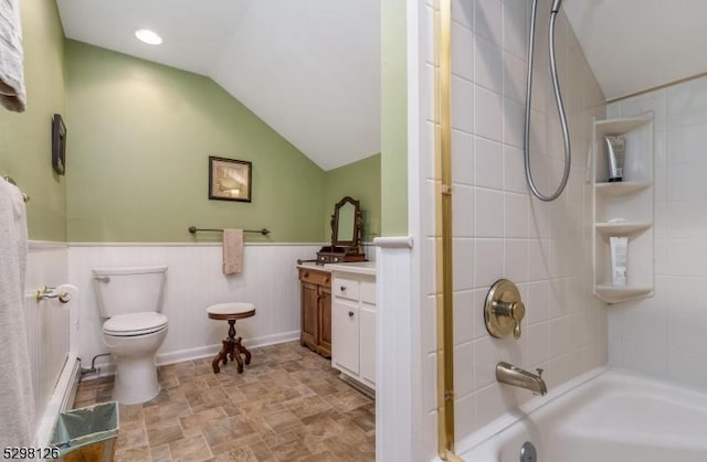 full bath featuring vanity, lofted ceiling, wainscoting, toilet, and shower / bathtub combination