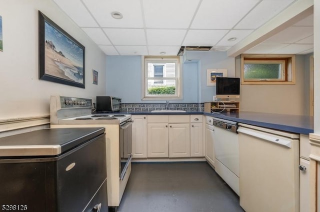 kitchen with dark countertops, dishwasher, electric stove, and a sink