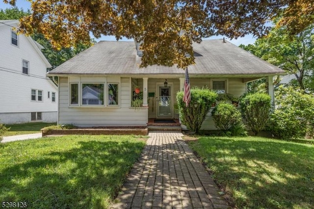 view of front facade with a front lawn, a porch, and a shingled roof