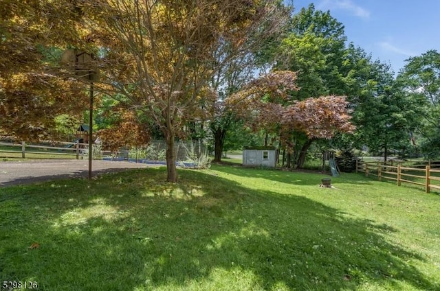 view of yard featuring a storage shed, an outdoor structure, and fence