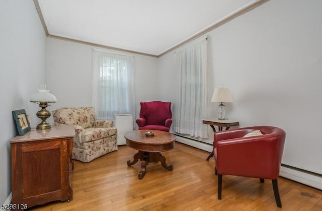 living area featuring light wood-type flooring, a baseboard radiator, ornamental molding, and a baseboard heating unit