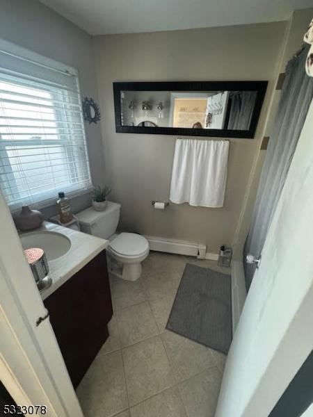bathroom featuring toilet, vanity, tile patterned flooring, and baseboard heating