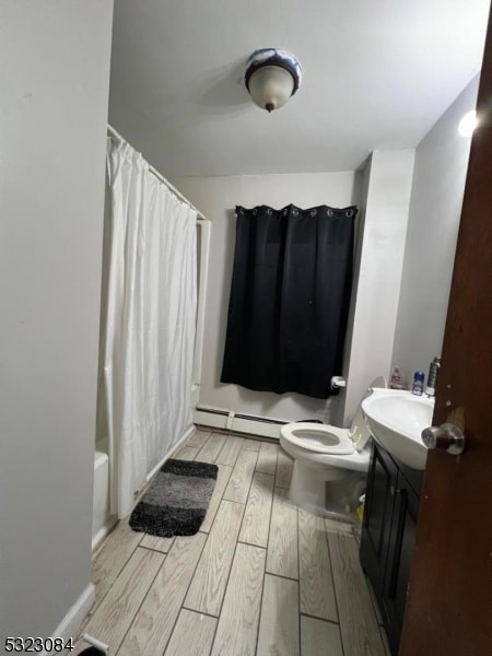 full bathroom featuring vanity, shower / bath combo, hardwood / wood-style floors, a baseboard heating unit, and toilet