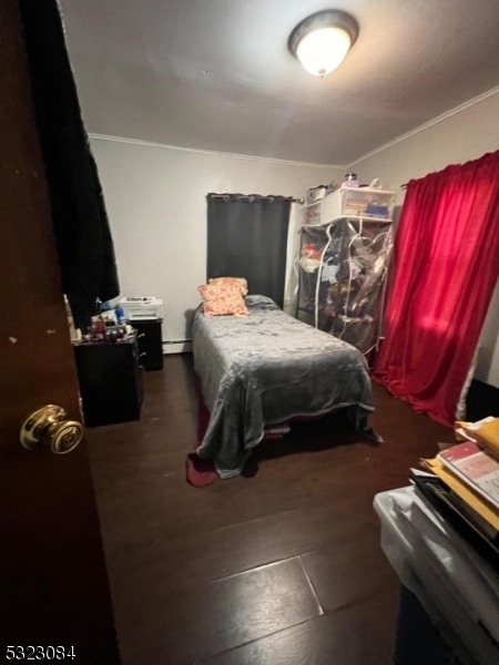 bedroom with dark wood-type flooring and a baseboard radiator