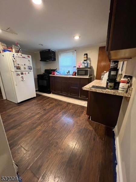 kitchen with dark brown cabinets, dark hardwood / wood-style flooring, black appliances, and light stone countertops