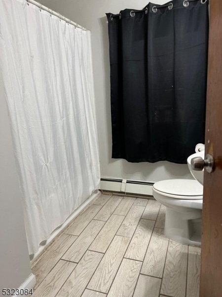 bathroom featuring toilet, hardwood / wood-style floors, and a baseboard radiator