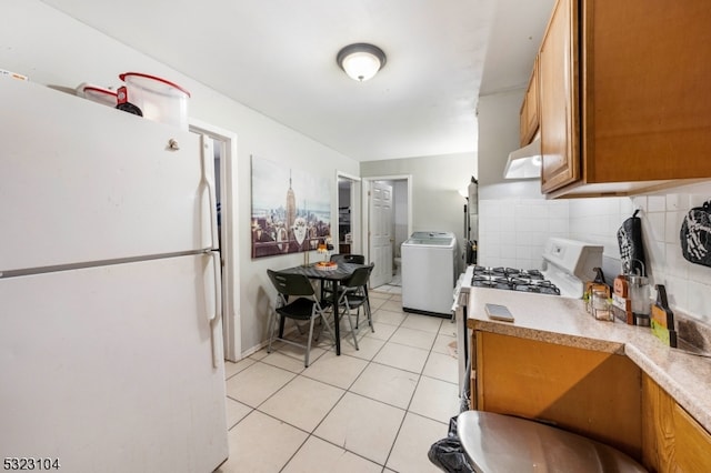 kitchen featuring light tile patterned floors, backsplash, washer / clothes dryer, white appliances, and ventilation hood