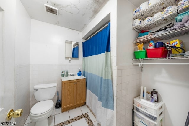 bathroom with tile walls, tile patterned floors, vanity, curtained shower, and toilet