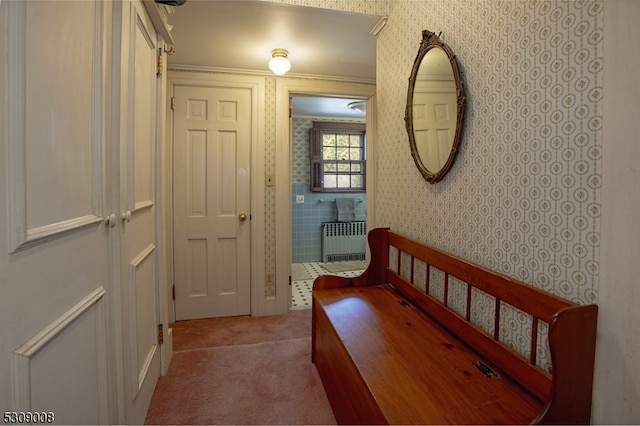 hall featuring radiator heating unit, light carpet, and ornamental molding