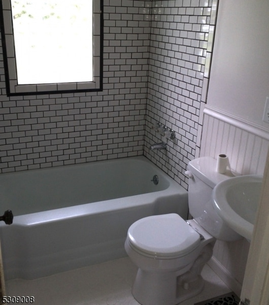 bathroom with toilet and tiled shower / bath