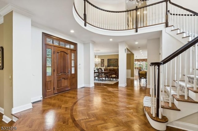 entrance foyer featuring baseboards, a high ceiling, a chandelier, and ornamental molding