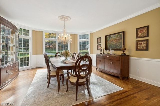 dining area featuring light wood finished floors, plenty of natural light, a chandelier, and crown molding