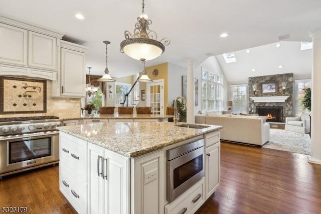 kitchen with dark wood-style flooring, a fireplace, stainless steel appliances, lofted ceiling, and a sink