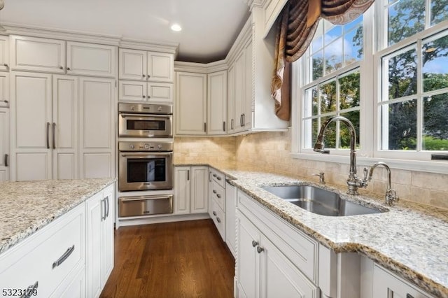 kitchen with double oven, tasteful backsplash, a sink, and a warming drawer