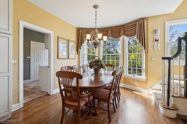 dining space featuring a notable chandelier, stairs, baseboards, and wood finished floors