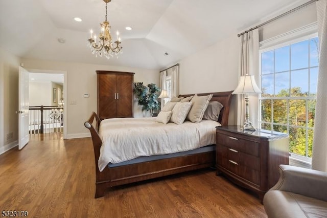 bedroom featuring multiple windows, vaulted ceiling, baseboards, and wood finished floors