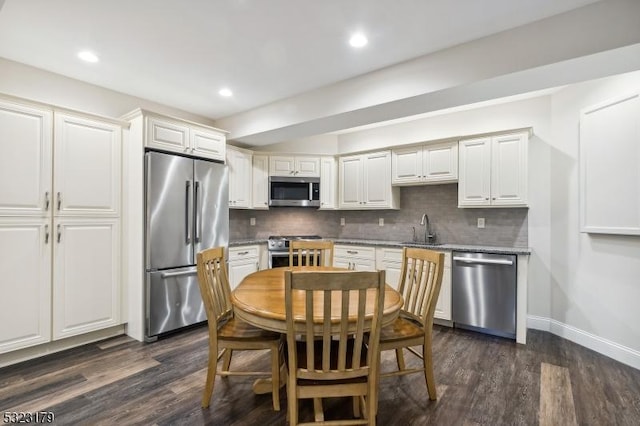 kitchen with appliances with stainless steel finishes, dark wood-style flooring, white cabinets, and decorative backsplash