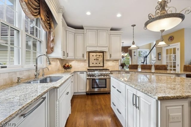 kitchen featuring high end stove, a sink, hanging light fixtures, decorative backsplash, and dark wood finished floors