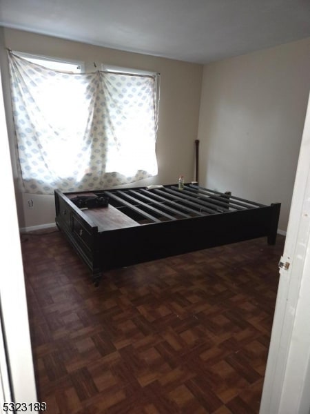 unfurnished bedroom featuring dark parquet flooring