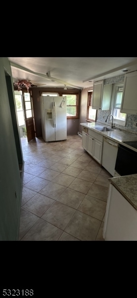 kitchen with backsplash, light tile patterned floors, sink, white cabinets, and white appliances