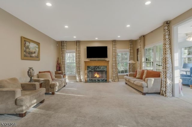 living room featuring light carpet, a wealth of natural light, and a premium fireplace