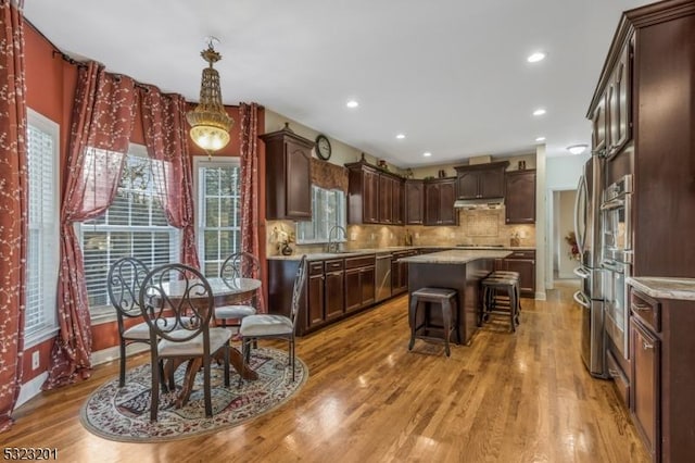 kitchen featuring tasteful backsplash, sink, a center island, dark brown cabinetry, and light hardwood / wood-style flooring