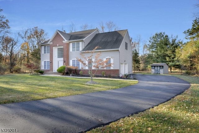 view of front of property with a storage unit, a front lawn, and a garage