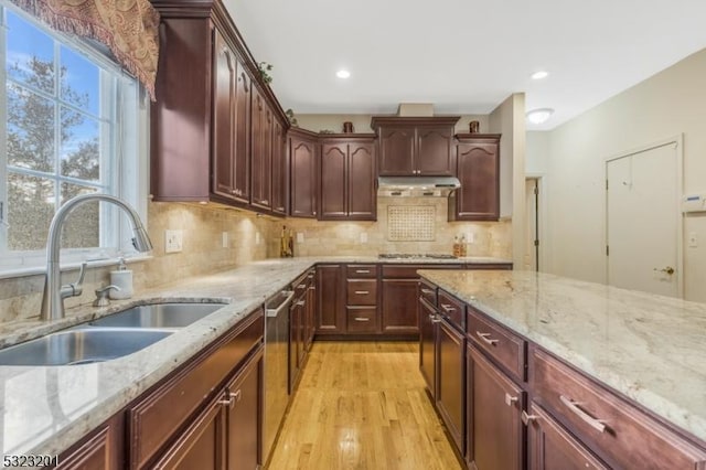 kitchen with sink, appliances with stainless steel finishes, light stone countertops, light hardwood / wood-style floors, and decorative backsplash