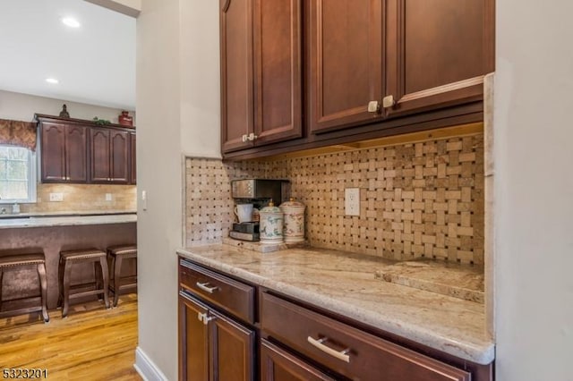 kitchen featuring tasteful backsplash, light stone counters, and light hardwood / wood-style flooring