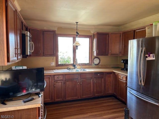 kitchen featuring crown molding, stainless steel appliances, dark hardwood / wood-style flooring, pendant lighting, and sink