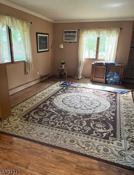 interior space with an AC wall unit, wood-type flooring, crown molding, and a baseboard heating unit