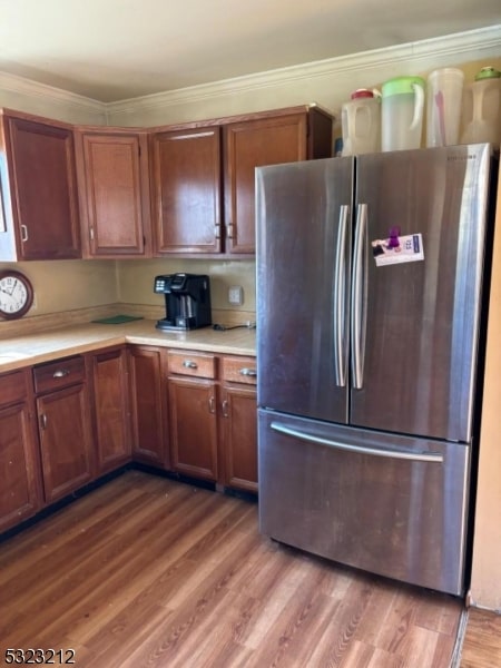 kitchen with ornamental molding, wood-type flooring, and stainless steel fridge