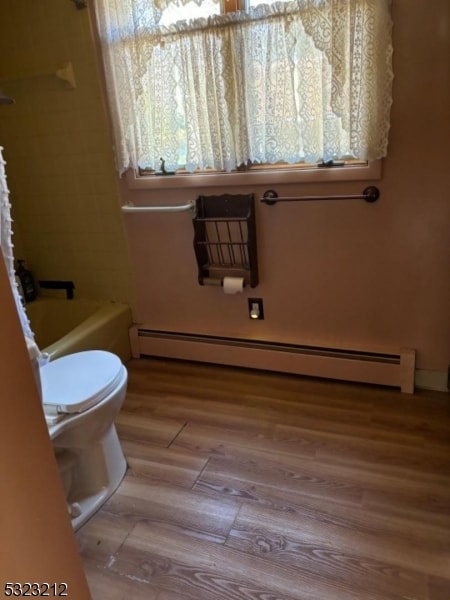 bathroom featuring a bathtub, hardwood / wood-style floors, a baseboard radiator, and toilet