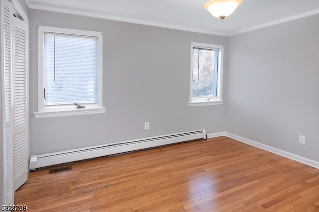 unfurnished room with crown molding, light wood-type flooring, and a baseboard heating unit